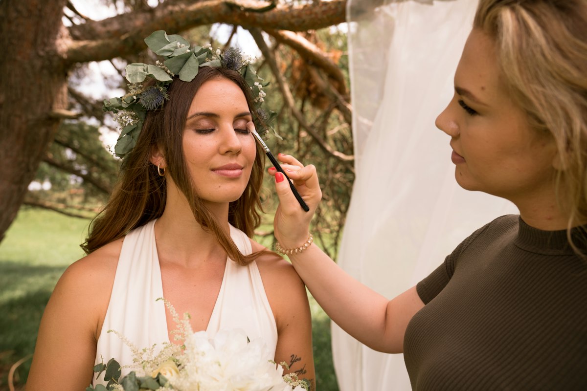 Makeup artist care retușează machiajul unei mirese, afară